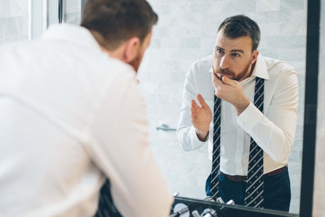 Man with beard looking in mirror