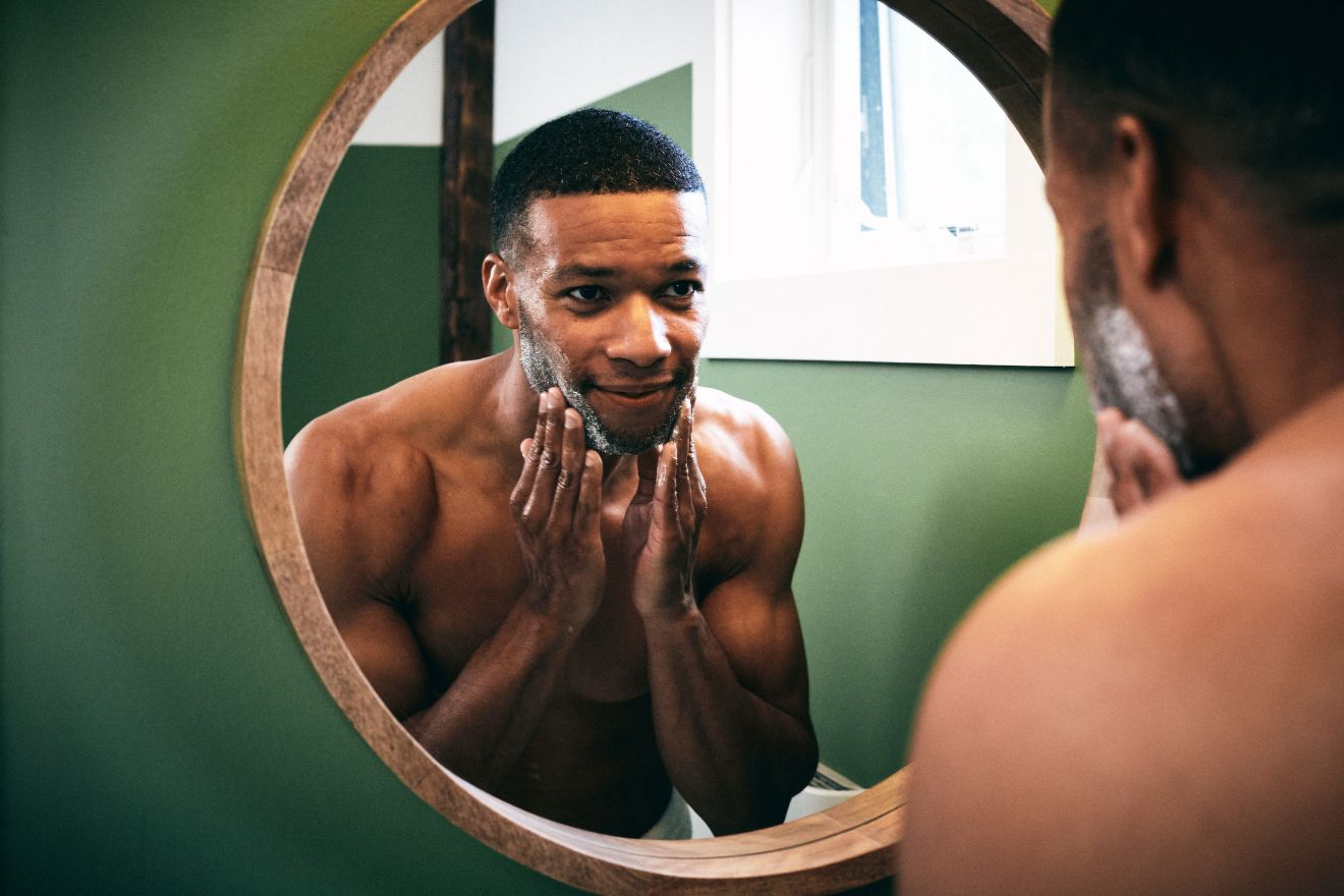 Man looking in mirror touching his face