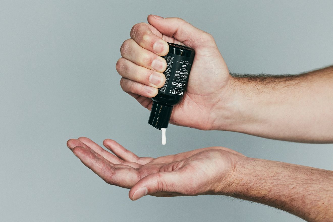 Man squeezing spf moisturizer from bottle