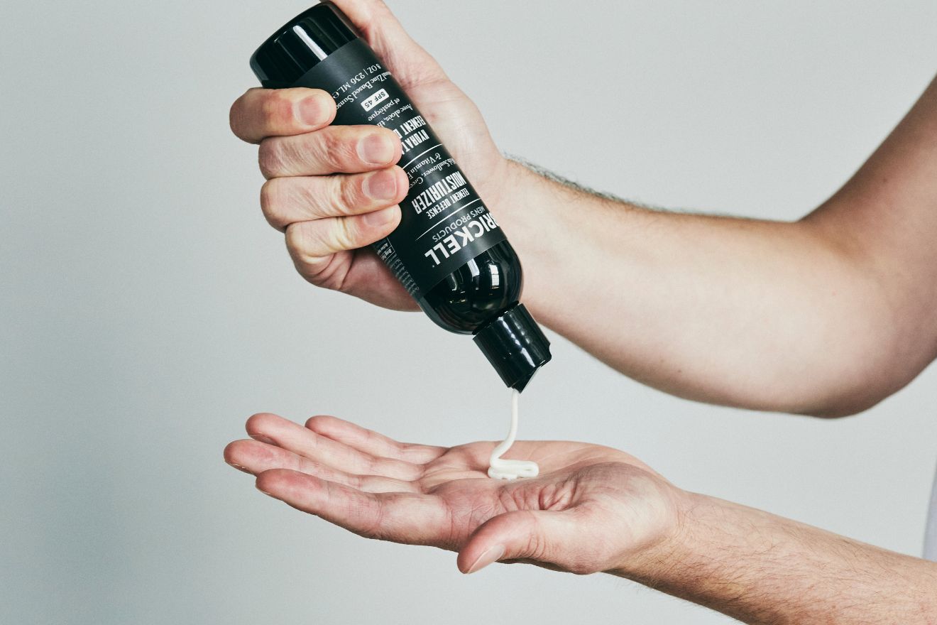 Hand squeezing sunscreen from bottle